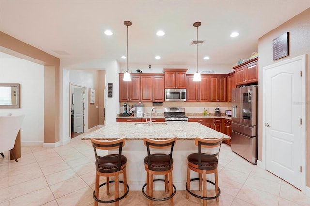 kitchen with sink, stainless steel appliances, pendant lighting, a kitchen bar, and a center island with sink