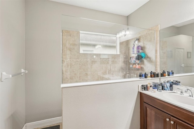 bathroom with tiled shower and vanity