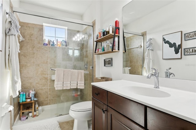 bathroom featuring tile patterned floors, vanity, a shower with shower door, and toilet