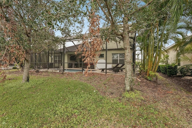 rear view of house with a lawn and a lanai