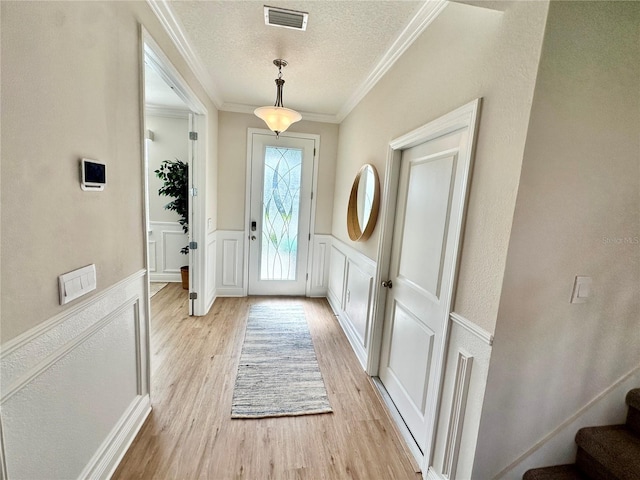 entryway featuring crown molding, a textured ceiling, and light wood-type flooring