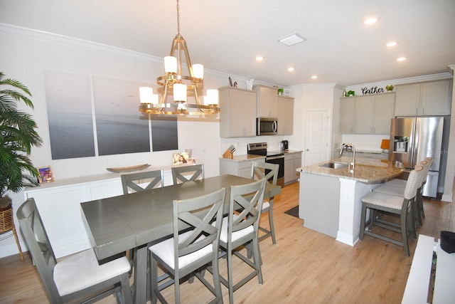 kitchen featuring gray cabinetry, sink, stainless steel appliances, crown molding, and a kitchen island with sink