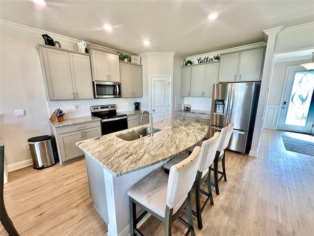 kitchen featuring gray cabinetry, a kitchen island with sink, sink, light hardwood / wood-style flooring, and stainless steel appliances