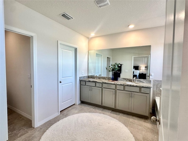 bathroom with tile patterned floors, a tub, vanity, and a textured ceiling