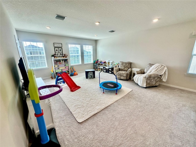 playroom with carpet floors and a textured ceiling