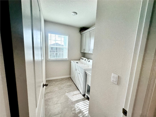 laundry area featuring cabinets, light tile patterned floors, a textured ceiling, and separate washer and dryer