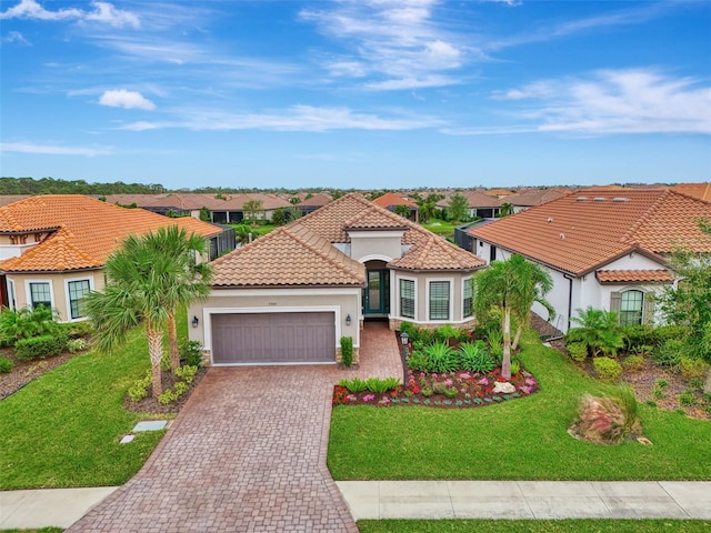 mediterranean / spanish-style home featuring a garage and a front lawn