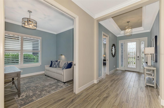 foyer featuring ornamental molding, wood-type flooring, and a chandelier