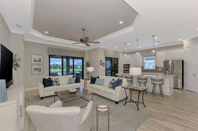 living room featuring ornamental molding, light hardwood / wood-style floors, and sink