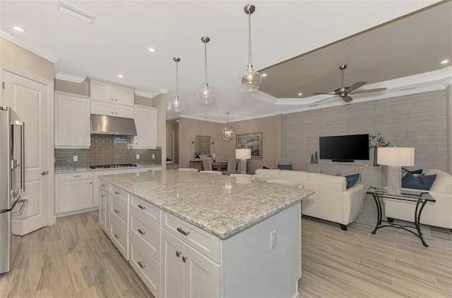 kitchen with crown molding, white cabinetry, stainless steel refrigerator, hanging light fixtures, and a center island