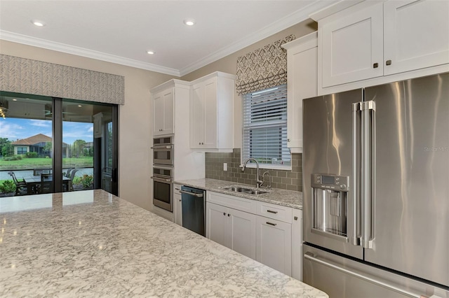 kitchen with light stone counters, white cabinets, sink, backsplash, and appliances with stainless steel finishes