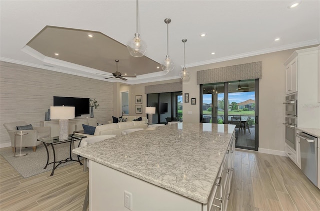 kitchen featuring light stone counters, white cabinetry, appliances with stainless steel finishes, pendant lighting, and a center island