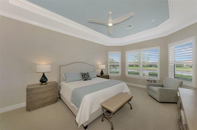 carpeted bedroom with ornamental molding, multiple windows, ceiling fan, and a tray ceiling