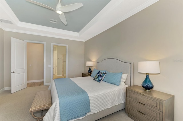 carpeted bedroom featuring ornamental molding, ensuite bathroom, ceiling fan, and a tray ceiling