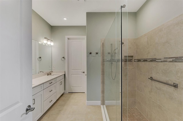 bathroom with tile patterned flooring, vanity, and a tile shower