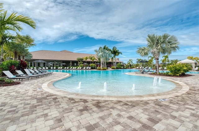 view of swimming pool with pool water feature and a patio area