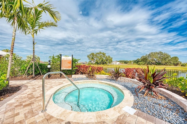 view of swimming pool featuring a water view and an in ground hot tub