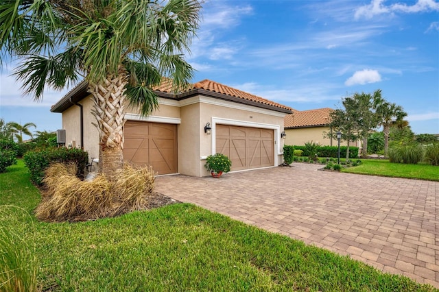 view of front of house featuring stucco siding, decorative driveway, a front lawn, and a garage