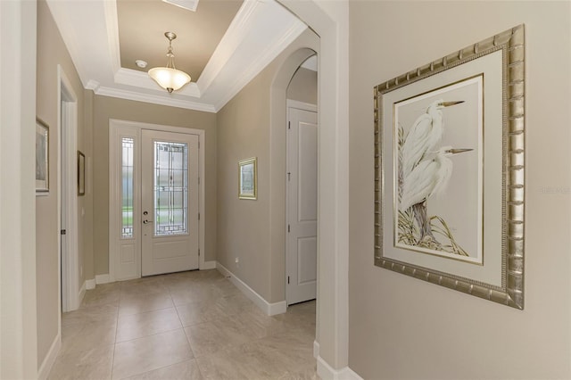 foyer with light tile patterned flooring, a tray ceiling, and ornamental molding