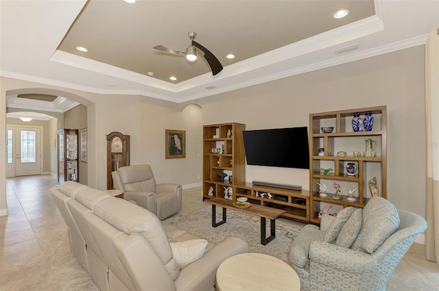 living room with ceiling fan, ornamental molding, light tile patterned floors, and a tray ceiling