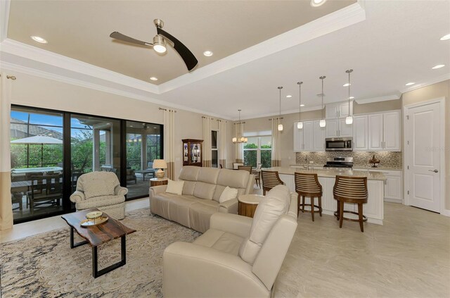 living room with ceiling fan, ornamental molding, and a raised ceiling