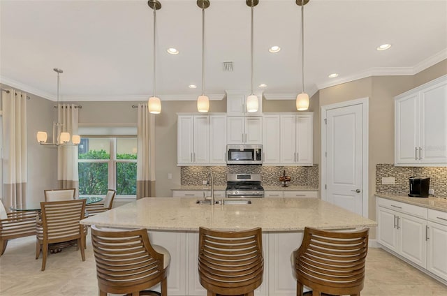 kitchen with stainless steel appliances, light stone countertops, hanging light fixtures, and white cabinetry