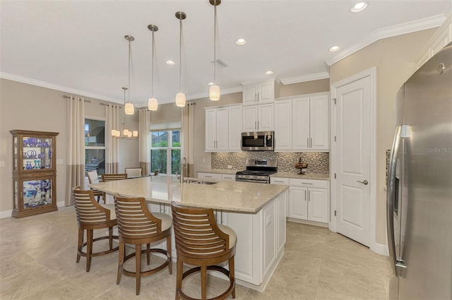 kitchen with white cabinetry, stainless steel appliances, decorative light fixtures, and an island with sink