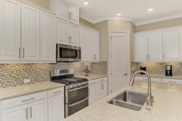 kitchen with stainless steel appliances, white cabinets, sink, and backsplash