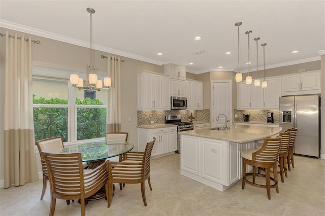 kitchen featuring a center island with sink, sink, appliances with stainless steel finishes, crown molding, and white cabinets