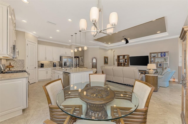 tiled dining space with sink, a chandelier, a raised ceiling, and crown molding