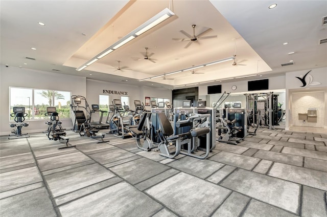 gym with a tray ceiling, ceiling fan, rail lighting, recessed lighting, and baseboards
