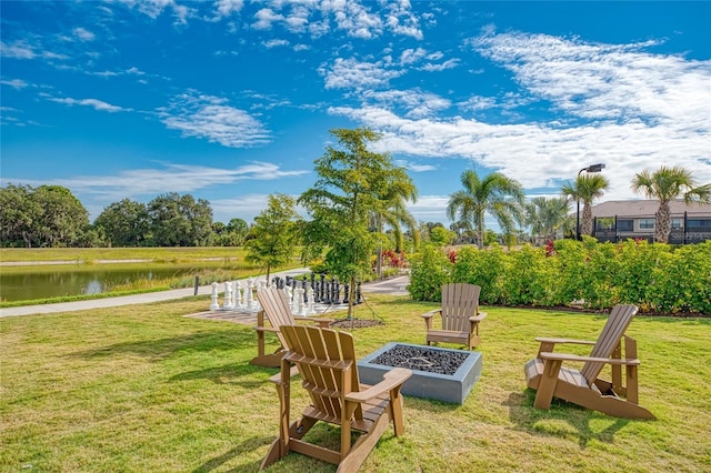 view of green lawn with an outdoor fire pit and a water view