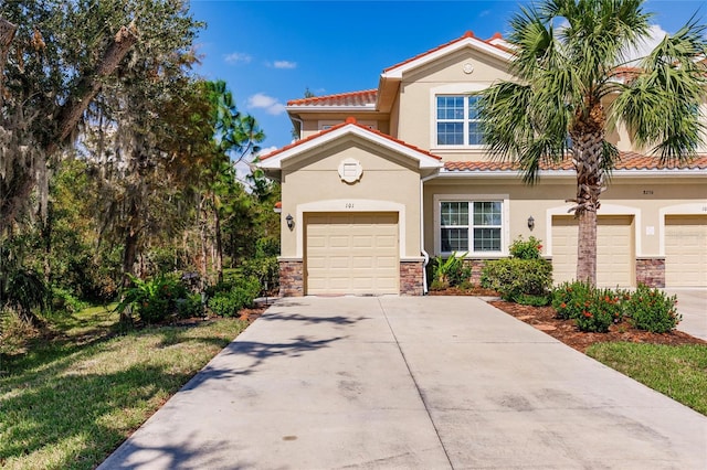 mediterranean / spanish house with a garage, stone siding, driveway, and stucco siding