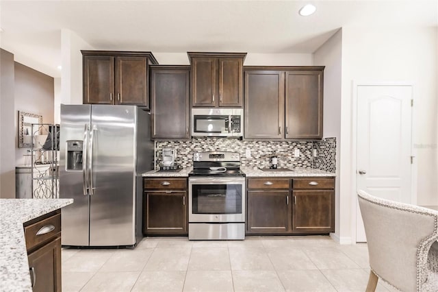 kitchen featuring light stone counters, decorative backsplash, appliances with stainless steel finishes, light tile patterned flooring, and dark brown cabinets