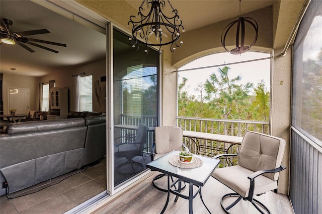 sunroom featuring ceiling fan with notable chandelier