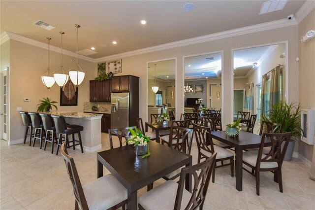 dining room featuring baseboards, visible vents, and crown molding