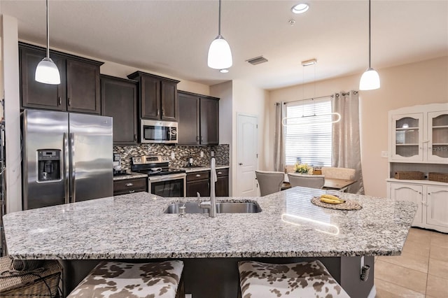 kitchen with tasteful backsplash, visible vents, stainless steel appliances, a kitchen bar, and a sink