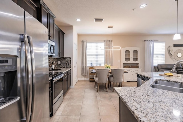 kitchen featuring light tile patterned flooring, stainless steel appliances, a sink, visible vents, and tasteful backsplash