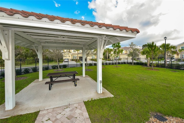 view of home's community with a patio, a lawn, and fence