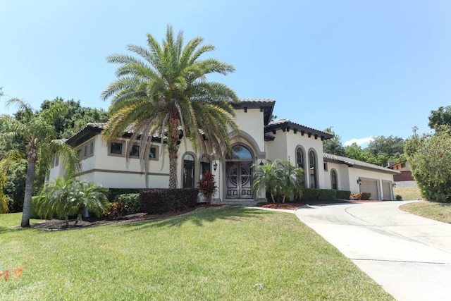 mediterranean / spanish house with a garage and a front lawn