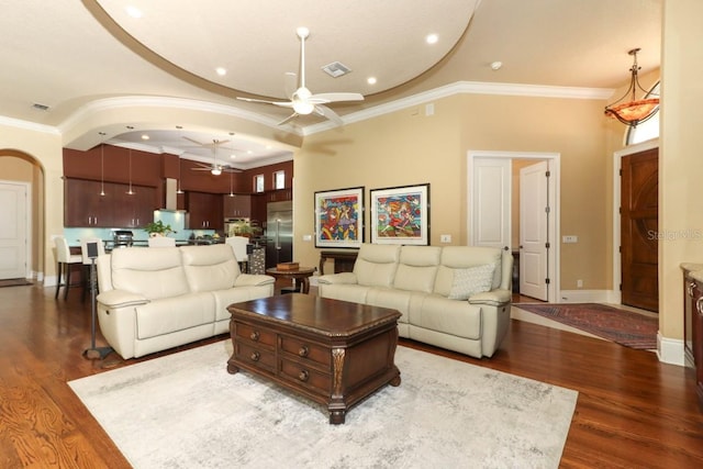 living room with dark wood-type flooring, ceiling fan, and crown molding