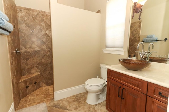 bathroom featuring a tile shower, vanity, and toilet