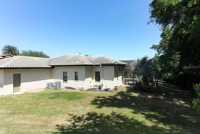 rear view of property with a lawn and cooling unit