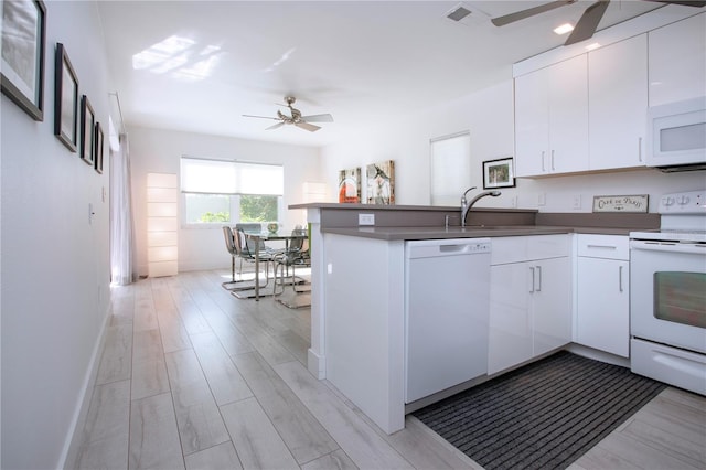 kitchen with kitchen peninsula, white cabinets, white appliances, and light wood-type flooring