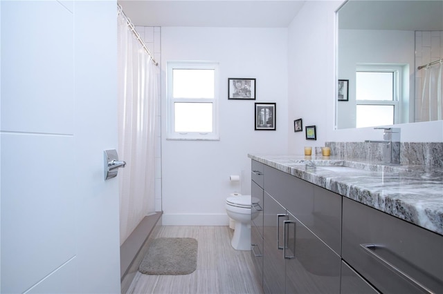 bathroom featuring plenty of natural light, vanity, a shower with shower curtain, and toilet