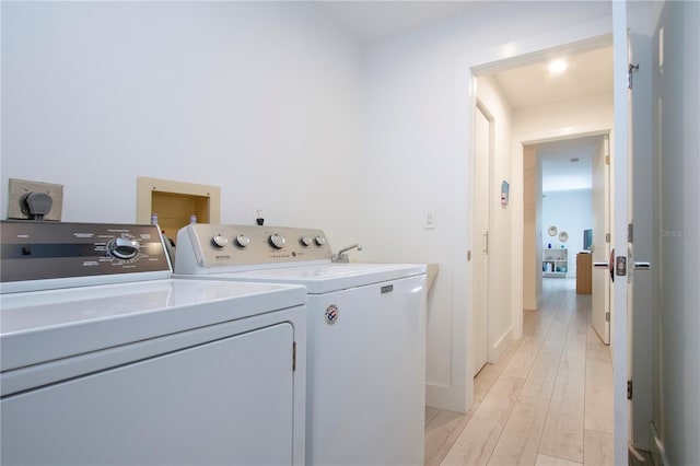 laundry area with washer and clothes dryer and light wood-type flooring