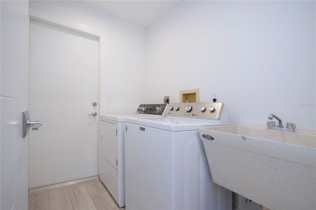 laundry room featuring separate washer and dryer, sink, and light hardwood / wood-style floors