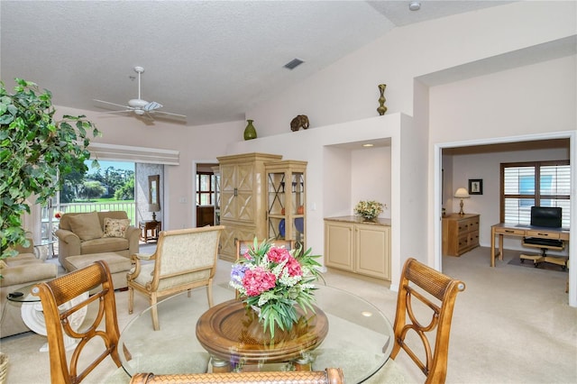 dining space with lofted ceiling, a textured ceiling, ceiling fan, and light carpet