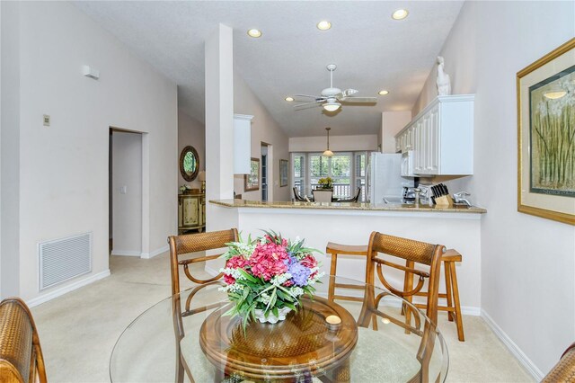 kitchen featuring kitchen peninsula, vaulted ceiling, light colored carpet, and white cabinets