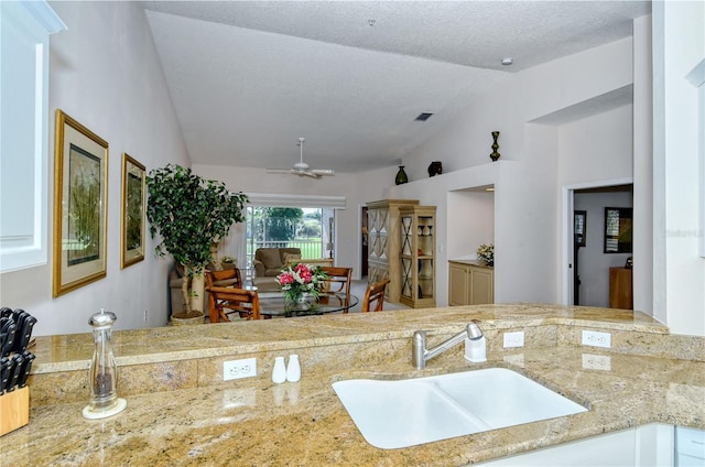 kitchen with white cabinetry, sink, ceiling fan, a textured ceiling, and vaulted ceiling